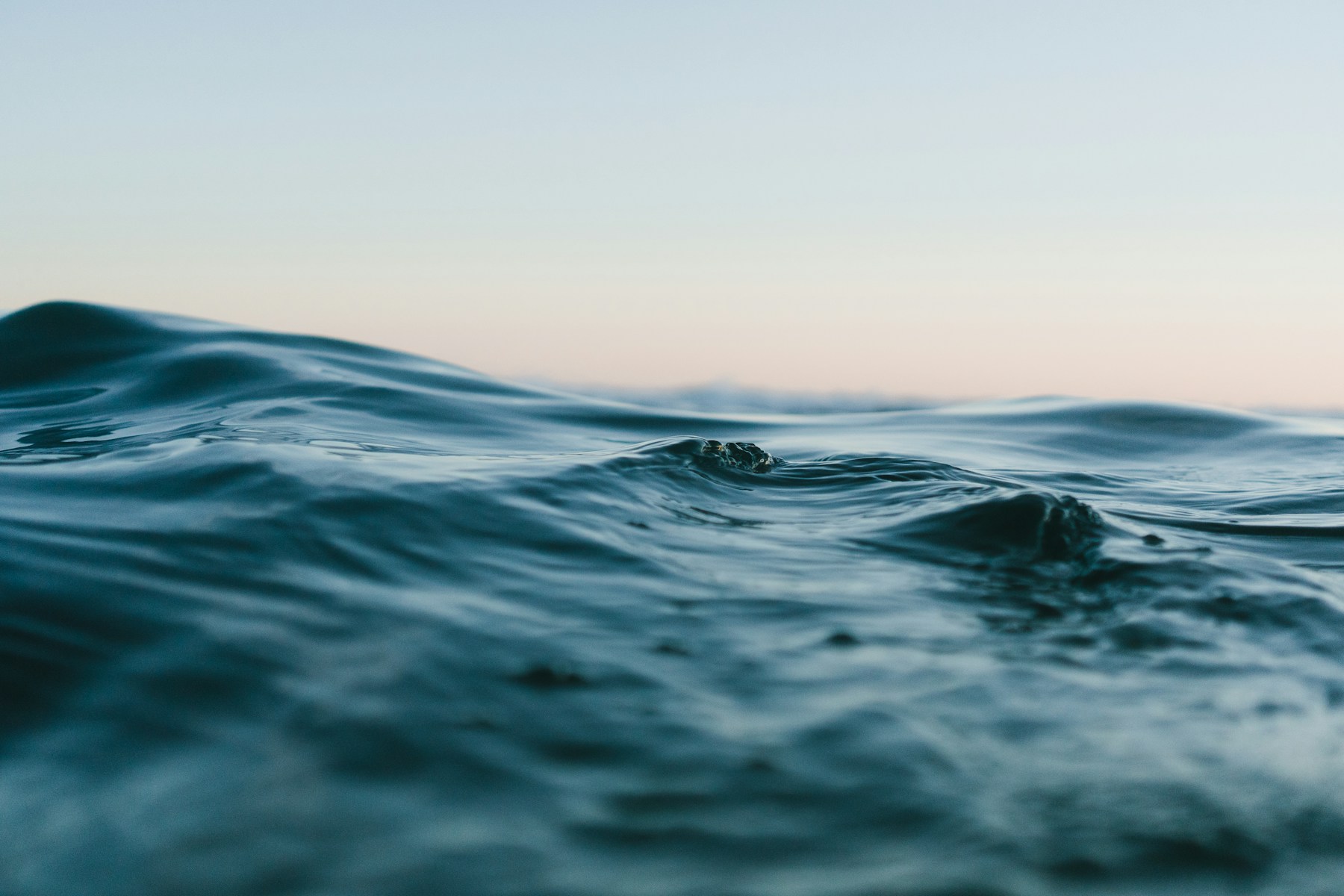 Calm blue ocean waves beneath a soft, open sky